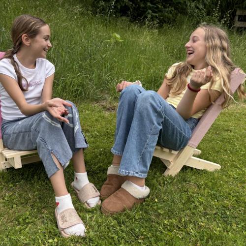 Zwei Schülerinnen unterhalten sich im Garten auf den Schwedenstühlen